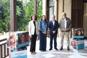 Cuatro personas posando junto a carteles de cursos de verano
