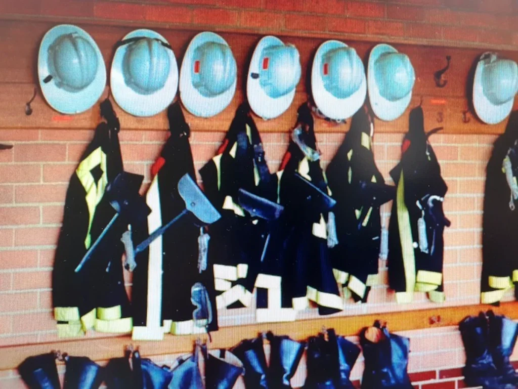 Casco y trajes de bomberos colgados en una pared