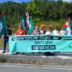 Manifestantes con banderas y pancarta en protesta frente a la nueva prisión de Donostia.