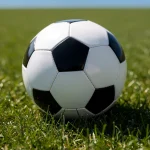 Balón de fútbol sobre césped verde en un campo deportivo