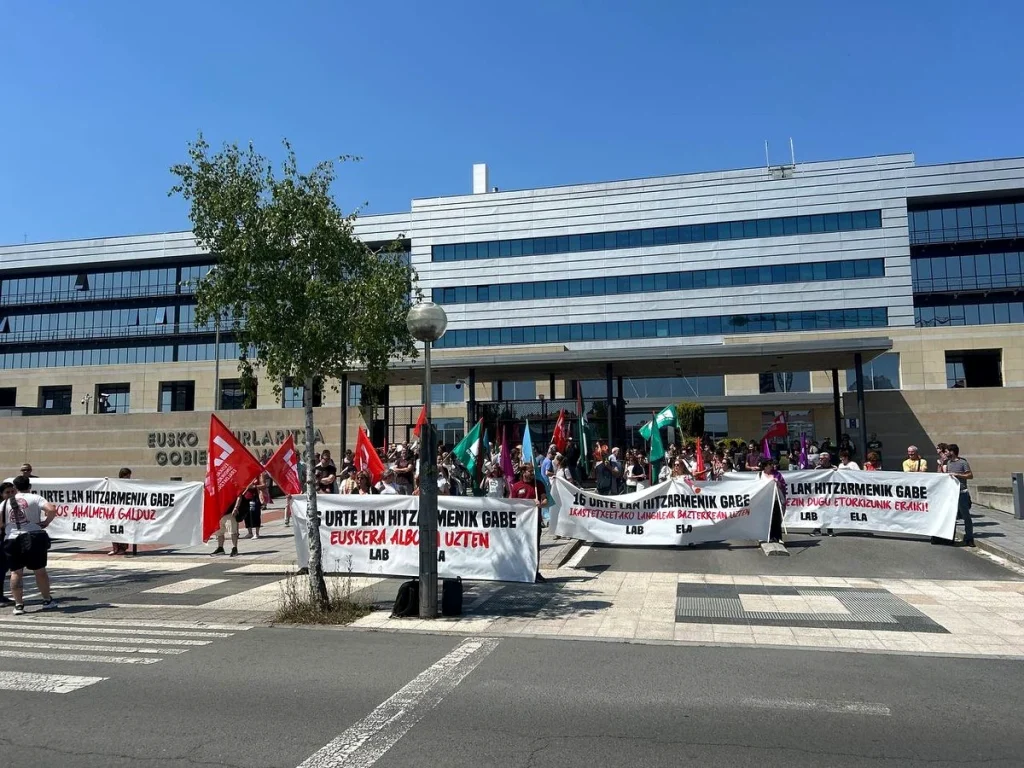 Manifestantes con pancartas en una protesta frente a un edificio.
