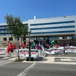 Manifestantes con pancartas en una protesta frente a un edificio.