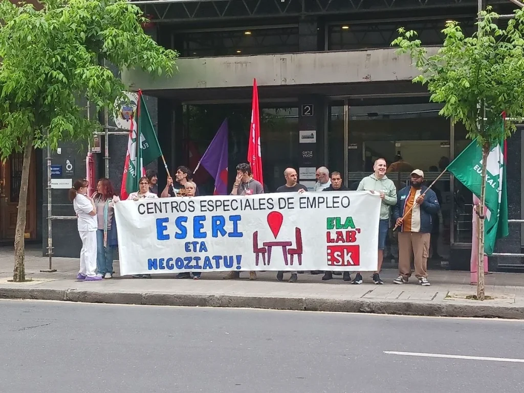 Manifestantes sosteniendo pancarta en protesta por convenio laboral