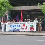 Manifestantes sosteniendo pancarta en protesta por convenio laboral