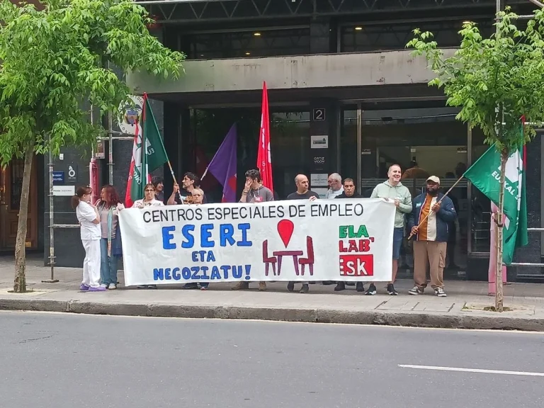 Manifestantes sosteniendo pancarta en protesta por convenio laboral