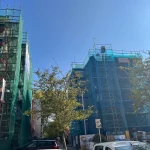 Edificios en rehabilitación con andamios y mallas verdes.