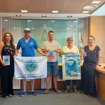 Grupo de personas sosteniendo banderas y carteles en una sala de reuniones