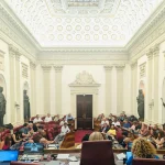 Sala de reuniones con personas sentadas y estatuas en las paredes