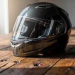 Casco de moto negro sobre una mesa de madera iluminada