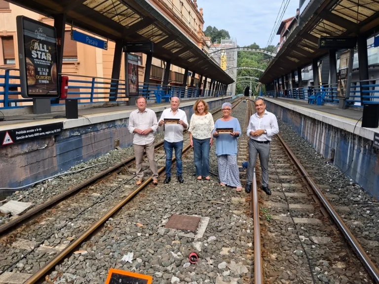 Grupo de personas en una estación de tren con vías visibles