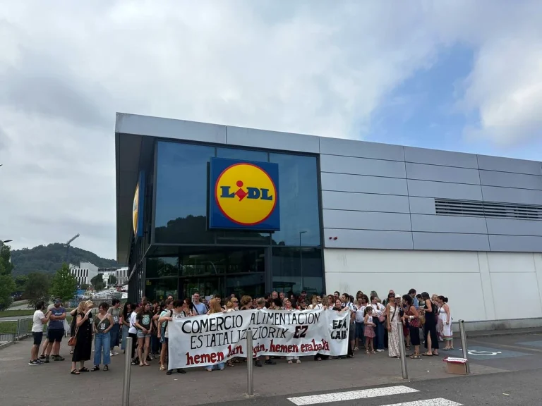 Grupo de personas protestando frente a un supermercado Lidl con pancarta.