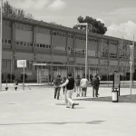 Grupo de personas en un campus universitario al aire libre.