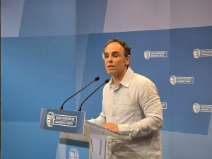 Hombre hablando en un podio con micrófonos en un evento oficial