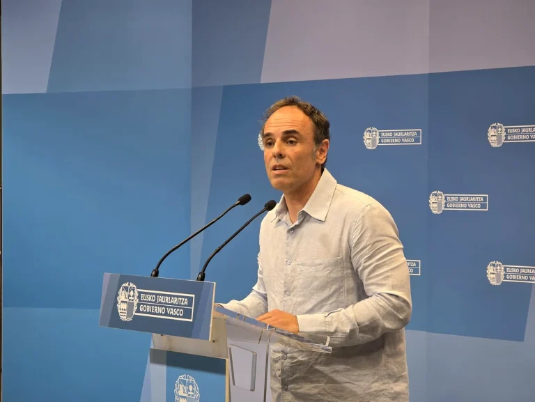 Hombre hablando en un podio con micrófonos en un evento oficial