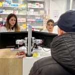 Dos farmacéuticas atendiendo a un cliente en una farmacia