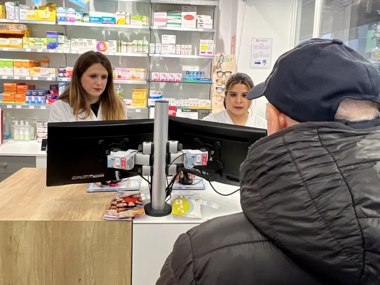 Dos farmacéuticas atendiendo a un cliente en una farmacia