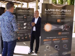 Persona hablando frente a paneles sobre eclipses lunares