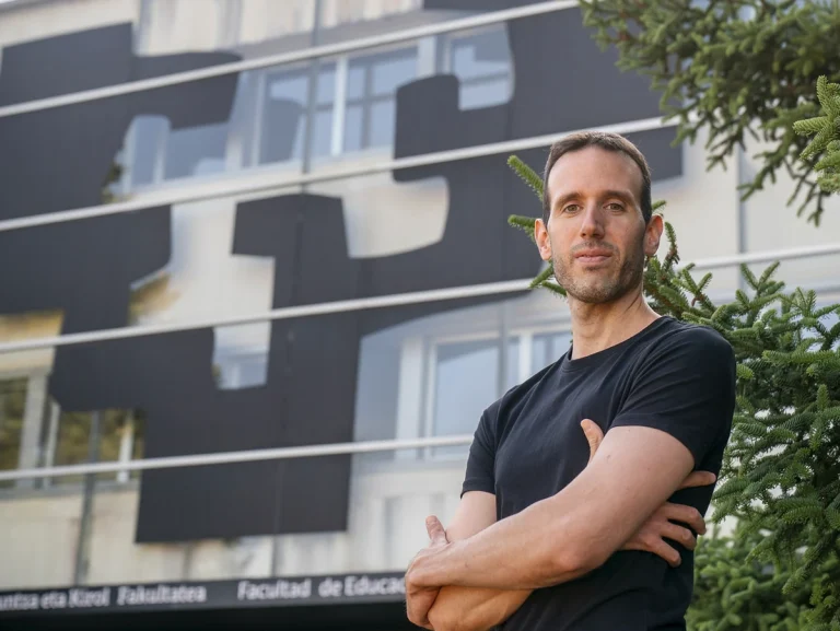 Hombre posando frente a un edificio moderno con diseño abstracto.