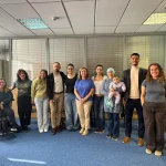 Grupo de personas en una sala de reuniones, algunas con discapacidad.